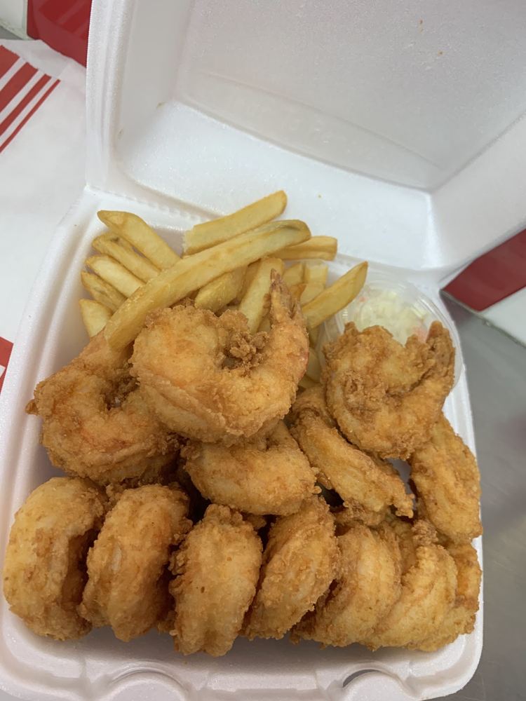 Breaded fried shrimp over fries in a JJ Fish takeout box