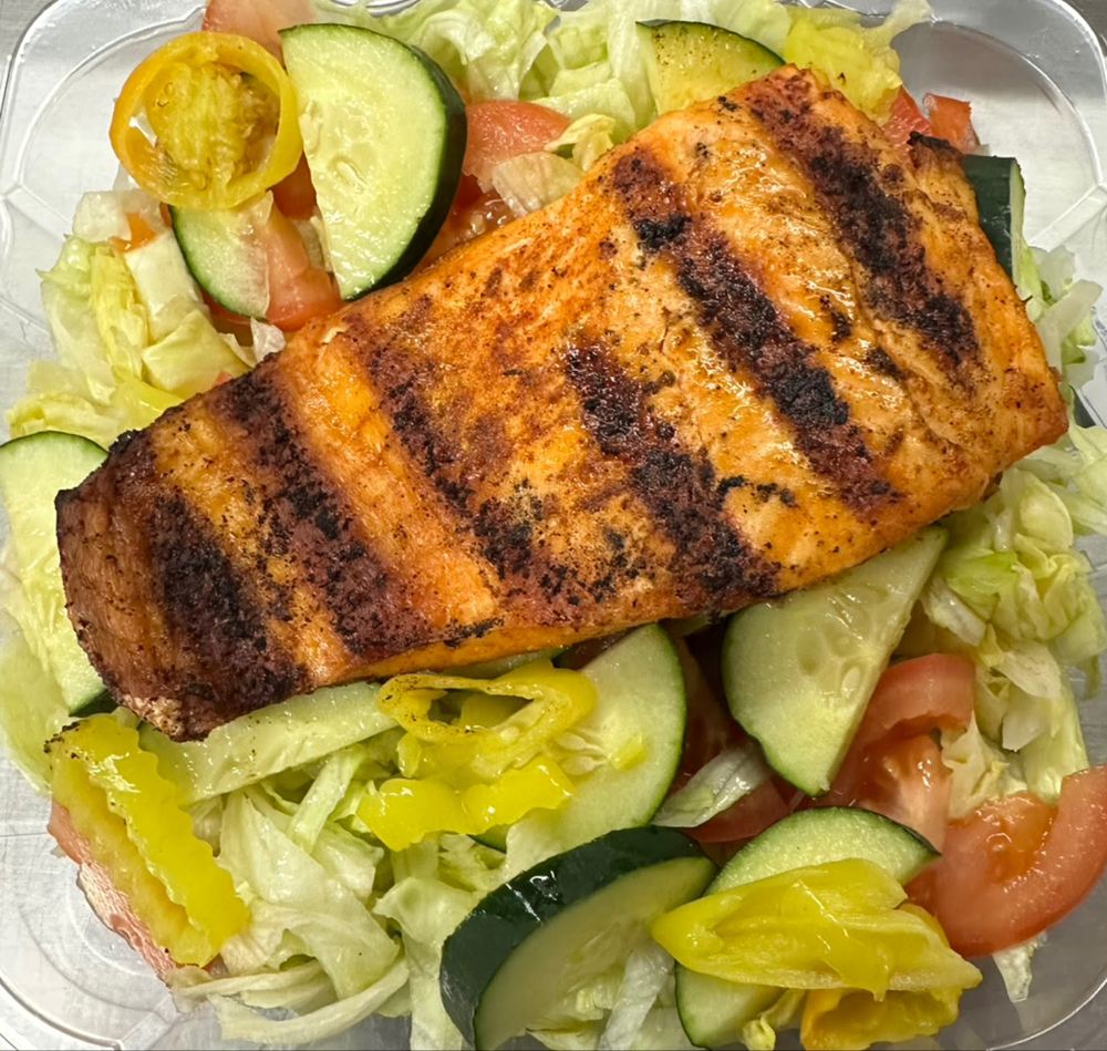 Grilled fish over a salad with cucumber, tomato and peppers